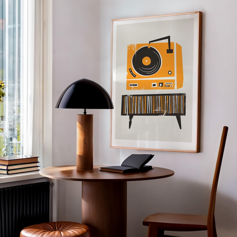 Puede incluir: Una impresi&oacute;n enmarcada de un tocadiscos vintage con un disco negro en un plato giratorio amarillo. El tocadiscos est&aacute; sobre un soporte de rayas blancas y negras con patas negras. La impresi&oacute;n est&aacute; sobre un fondo gris claro y tiene un marco de madera.