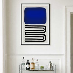 May include: A framed wall art print featuring a large solid blue rectangle positioned above a series of black horizontal lines that curve and connect in a continuous, stacked U-shape pattern, all set against a light gray background.
