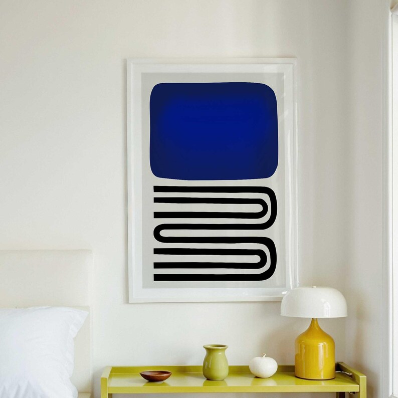 May include: A framed wall art print featuring a large solid dark blue rectangle positioned above a series of three stacked black horizontal U-shaped lines that create a continuous, repeating pattern on a light gray background.