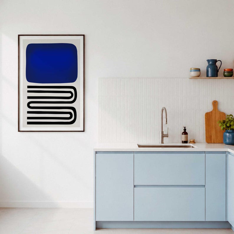 May include: A framed wall art print featuring a solid dark blue rectangle positioned above a series of black horizontal lines that form a continuous, repeating U-shaped pattern on a light gray background, displayed in a kitchen setting.