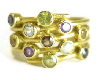 May include: A gold ring with multiple bands set with various gemstones, including amethyst, aquamarine, citrine, peridot, and topaz.