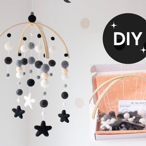 May include: DIY baby mobile kit with a wooden frame, white, gray, and black felt balls, and black felt stars. The kit comes with instructions and all the materials needed to assemble the mobile.