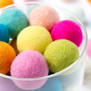May include: A glass jar filled with colourful felt balls. The balls are in various shades of pink, blue, green, yellow, and orange.