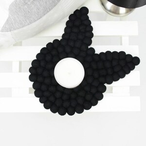 May include: Black felt coaster shaped like a star with a round indentation in the center for a candle.