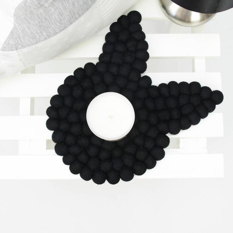 May include: Black felt coaster shaped like a star with a round indentation in the center for a candle.
