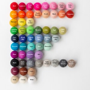 May include: A color chart of 2.5cm felt balls arranged in rows. The chart displays a wide variety of colors including red, pink, orange, yellow, green, blue, purple, grey, brown, and white, each labeled with its specific color name below the ball.