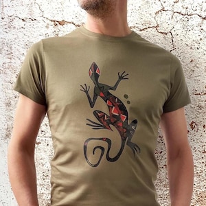 Könnte beinhalten: Ein grünes T-Shirt mit einem schwarzen und roten Eidechsen-Design. Die Eidechse ist stilisiert und hat ein geometrisches Muster.