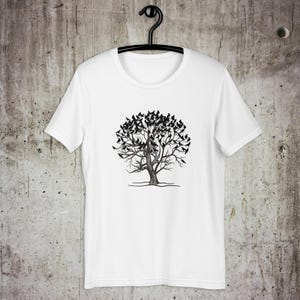 May include: White t-shirt with a black and white illustration of a tree with birds on the branches.