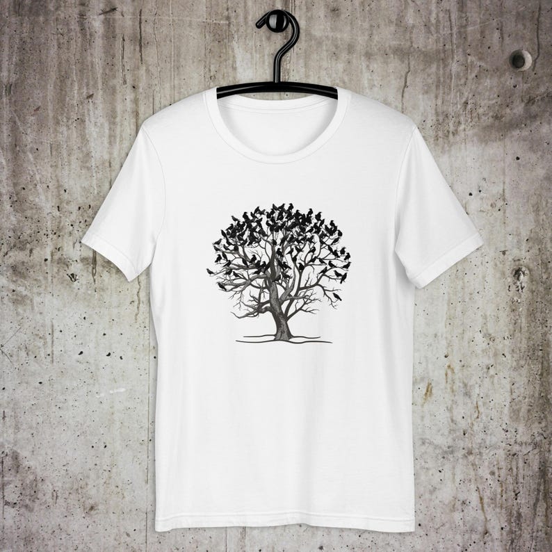 May include: White t-shirt with a black and white illustration of a tree with birds on the branches.