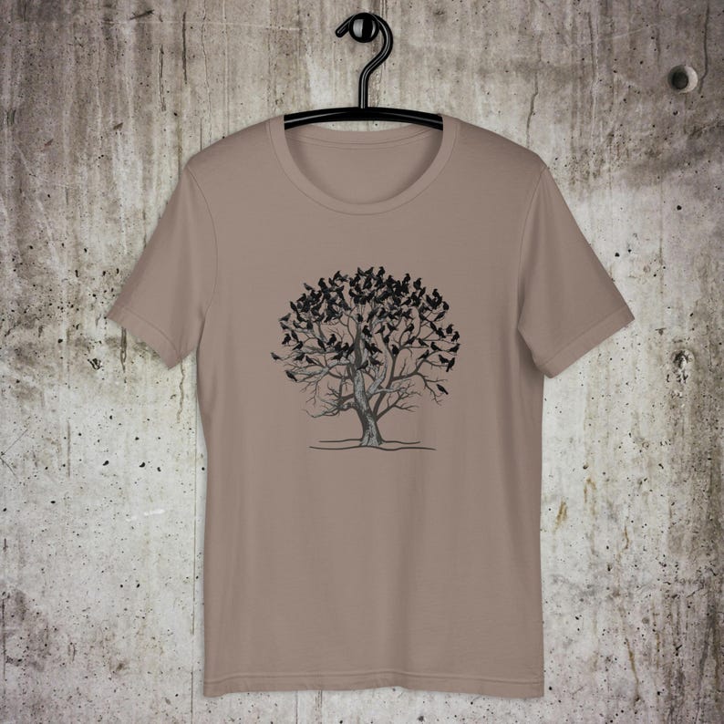 May include: A tan t-shirt with a black and white graphic of a tree with birds on the branches.