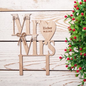 Puede incluir: Topper de pastel de madera con las palabras "Mr" y "Mrs" en un estilo r&uacute;stico. El topper incluye una pieza en forma de coraz&oacute;n con el texto "Eicher 06.22.2019".