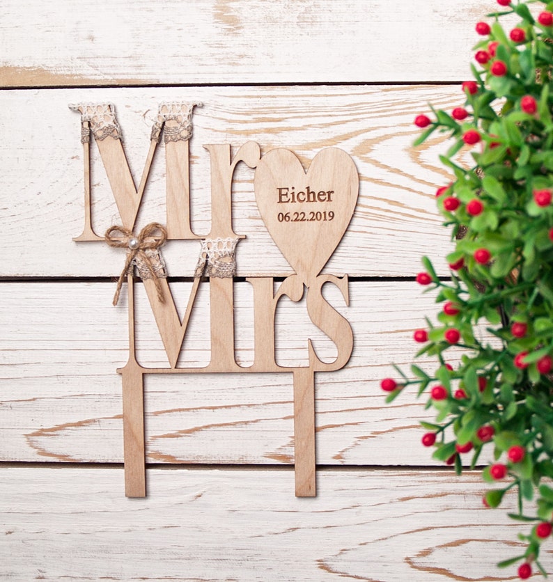 Puede incluir: Topper de pastel de madera con las palabras "Mr" y "Mrs" en un estilo r&uacute;stico. El topper incluye una pieza en forma de coraz&oacute;n con el texto "Eicher 06.22.2019".