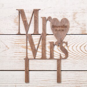 Puede incluir: Topper de pastel de madera "Mr. y Mrs." con un recorte en forma de coraz&oacute;n que dice "Brownlie 23.05.20".
