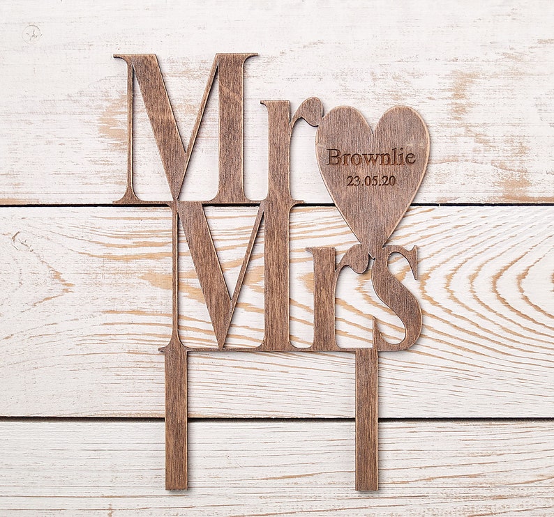 Puede incluir: Topper de pastel de madera "Mr. y Mrs." con un recorte en forma de coraz&oacute;n que dice "Brownlie 23.05.20".