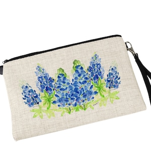 May include: A beige canvas zippered pouch with a black zipper and a black wrist strap. The pouch features a watercolor painting of bluebonnet flowers on a white background.