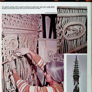 May include: A woman in a striped shirt is working on a large macrame wall hanging. The hanging is made of natural colored rope and is being created using simple knots. The rope is secured to dowels to help support the weight of the hanging.