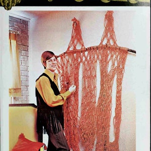 May include: A large macrame wall hanging made with orange cord and a branch. The macrame is knotted with square knots in a variety of alternating patterns.