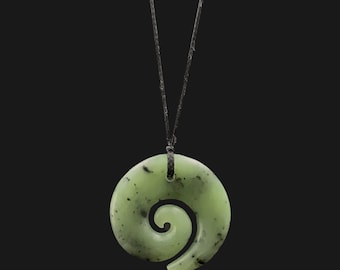 May include: A green jade pendant necklace with a spiral design. The pendant is on a black cord.