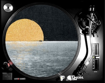 May include: A black and gold vinyl record slipmat with a design of a sunset over a body of water. The slipmat is on a turntable with a tonearm.