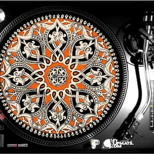 May include: A black and orange patterned turntable slipmat with a geometric design. The slipmat is on a black turntable with a silver tone tonearm.