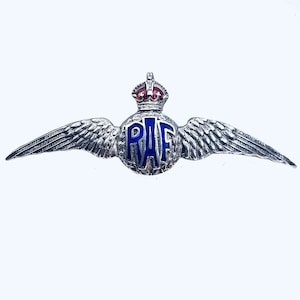 May include: A silver pin with a blue enamel circle featuring the letters "RAF" and a red and gold crown. The circle is surrounded by silver wings.