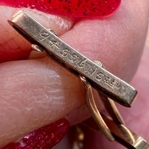 May include: Close-up of a gold cufflink with the inscription "14K 585 1.5gr" on the back.