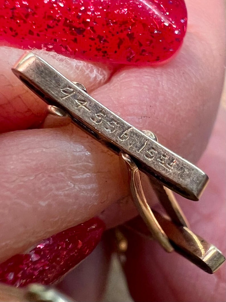 May include: Close-up of a gold cufflink with the inscription "14K 585 1.5gr" on the back.