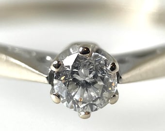 May include: A silver ring with a single round diamond set in a six-prong setting.