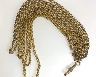 May include: A gold chain with a tarnished finish and a hook clasp. The chain is made of multiple strands of linked circles.