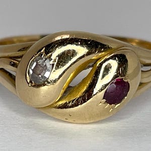 May include: A gold ring with a twisted design, set with a small ruby and a diamond.
