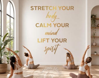 May include: Four people performing yoga in a bright room. The wall features gold lettering that reads "STRETCH YOUR body, CALM YOUR mind, LIFT YOUR spirit". The yoga participants wear white tops and neutral-toned bottoms.