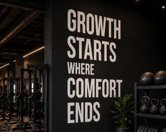 Puede incluir: Una pared negra en un gimnasio con el texto blanco "GROWTH STARTS WHERE COMFORT ENDS" en una fuente sans-serif negrita. A la derecha, un estante de metal negro sostiene pesas rusas y discos negros, junto a una planta verde en maceta.