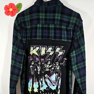 May include: A long-sleeved, button-down shirt with a plaid pattern in shades of blue and green. The back features a black patch with the band KISS logo and band members. The word "DESTROYER" is printed below the band members.