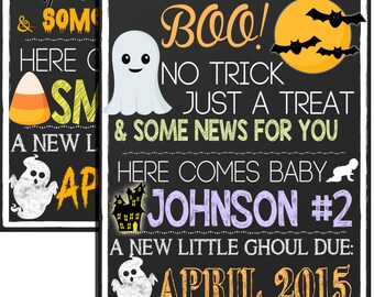 Op de afbeelding: Twee zwarte schoolborden met een Halloween-thema kondigen de komst van een nieuwe baby aan. Het bovenste bord zegt "Boo! No trick just a treat" met een spinnenweb en een spin. Het onderste bord zegt "Boo! No trick just a treat & some news for you. Here comes baby Johnson #2. A new little ghoul due: April 2015" met een spook, een spookhuis en een kruipende baby.