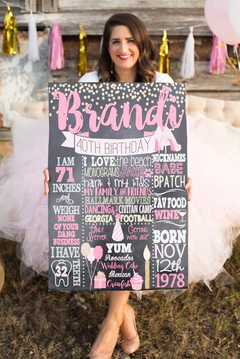 Puede incluir: Un letrero de pizarra negra con detalles de purpurina dorada y letras rosas. El letrero dice "Brandi 40th Birthday" e incluye detalles sobre la persona que cumple a&ntilde;os, como su altura, peso, comidas favoritas y fecha de nacimiento.