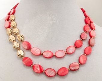 Collar babero de dos hebras con cuentas de concha marina dorada y coral.