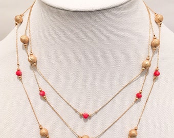 Collar babero de tres hilos en coral y oro.