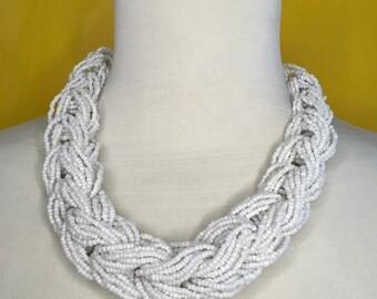 Collar babero con cuentas de semillas trenzadas de múltiples hilos de color blanco.