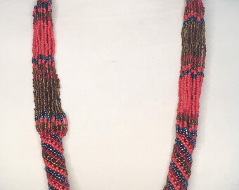 Collar largo de cuentas de semillas rojas y cobre.