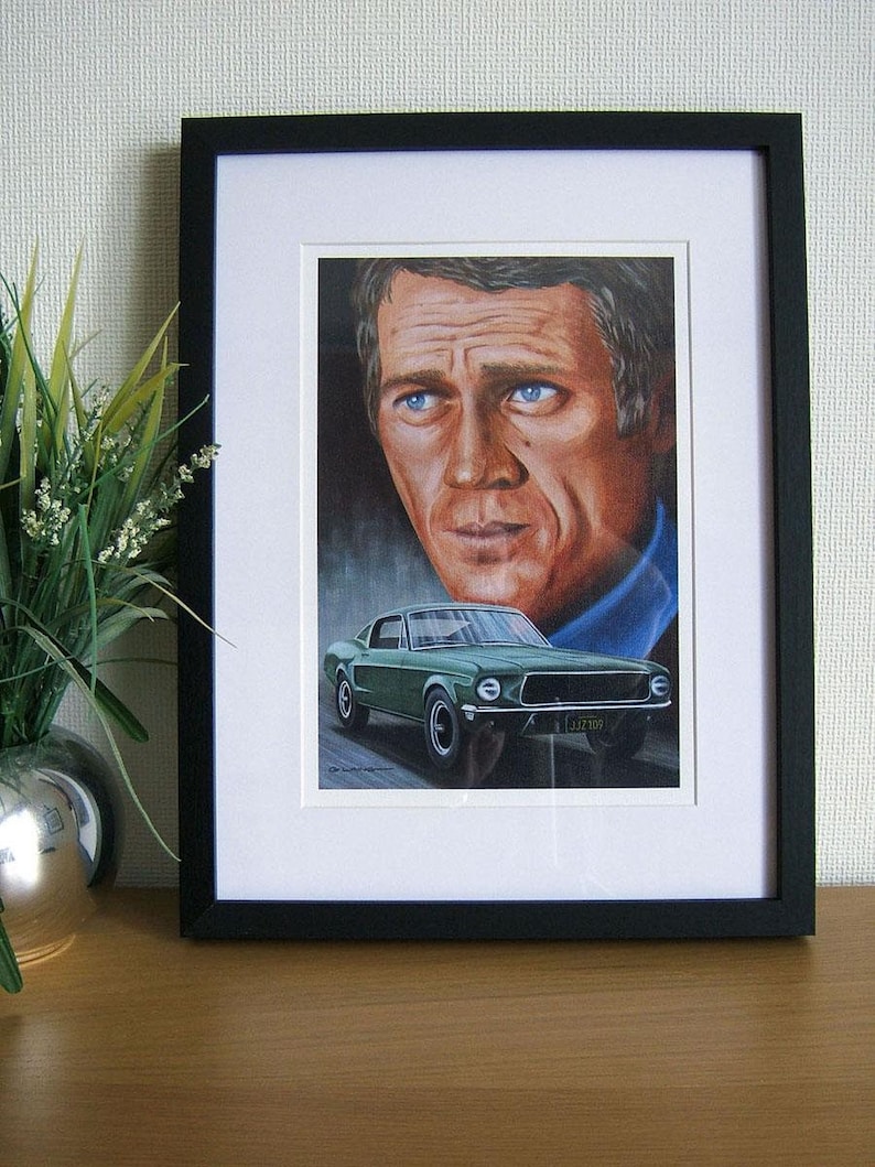 May include: A framed print of a portrait of a man with a green Ford Mustang in the background. The man has blue eyes and is wearing a blue shirt. The car has a California license plate.
