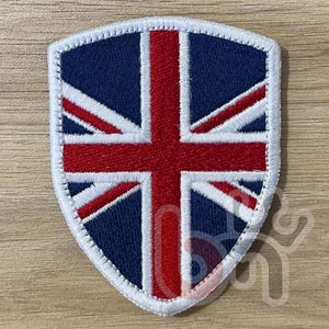 May include: A white shield-shaped patch with an embroidered Union Jack flag in red, white, and blue.