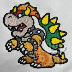 May include: An embroidered patch featuring a cartoon character with a tan snout, orange hair, and a green shell adorned with yellow spikes. The character has grey spiked wristbands, orange skin, and white claws, all outlined in thick black thread.