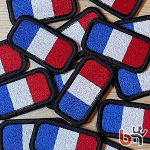 May include: A collection of embroidered patches featuring the French flag colors of blue, white, and red. The patches are rectangular and have a black border.
