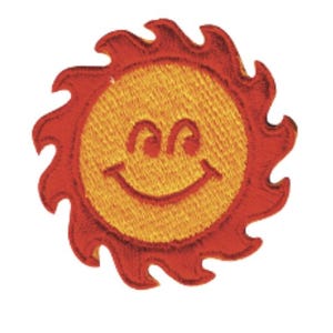 May include: A circular embroidered patch featuring a bright yellow sun face with a smiling expression, characterised by curved eyes and a wide grin. The sun is surrounded by jagged, flame-like red rays that extend outward from the central yellow disc.