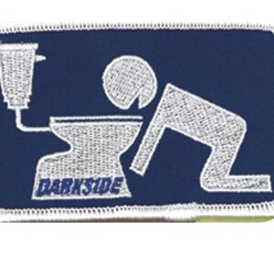 May include: A rectangular embroidered patch with a dark blue background and a white border. The design features a white embroidered graphic of a person leaning over a toilet, with the word DARKSIDE stitched in blue letters on the toilet base.