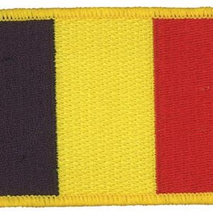 Op de afbeelding: Een rechthoekige geborduurde patch met de verticale driekleurige vlag van België. Het ontwerp bestaat uit drie gelijke verticale banen in zwart, geel en rood, afgewerkt met een dikke, gestikte gele rand rondom de gehele omtrek van de patch.