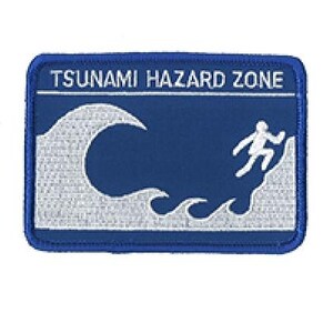 Peut inclure: Un écusson rectangulaire brodé avec un fond bleu et une bordure blanche. Il présente le texte TSUNAMI HAZARD ZONE en lettres capitales blanches au-dessus d'un graphique représentant une grande vague et un personnage bâton courant vers le haut.