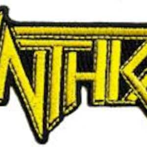 May include: Embroidered patch featuring the band name "ANTHRAX" in bold, yellow, stylized lettering. The text is outlined in black, creating a striking contrast. The patch has a black background and is likely designed to be sewn onto clothing or accessories.