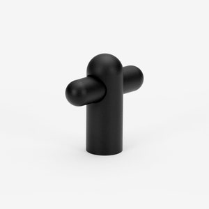 May include: Black cabinet knob with a rounded, cylindrical design. The knob has a cross-shaped handle with rounded ends.