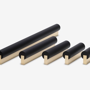 May include: Five black and brass cabinet pulls of varying lengths. The pulls are cylindrical with rounded ends and a rectangular base.